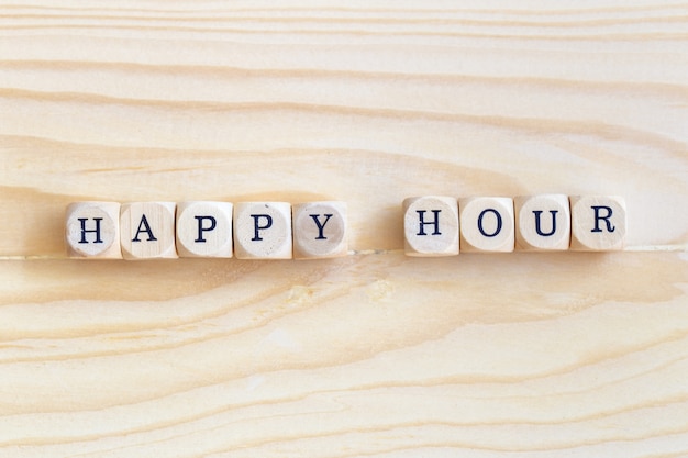 Happy hour, parola di viste superiori fatta dalle lettere di legno sulla tavola