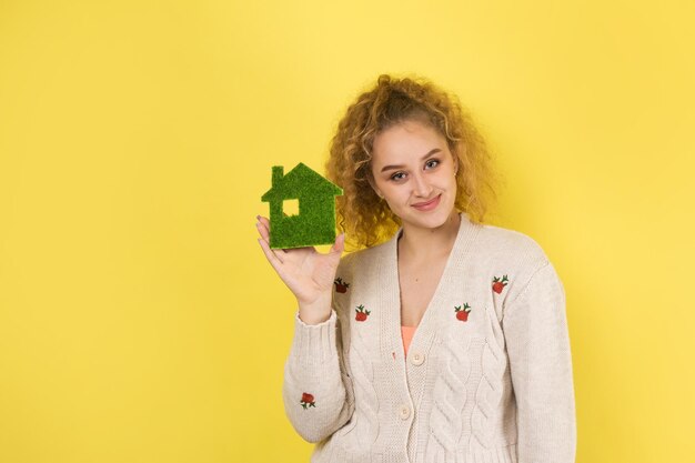 Счастливый покупатель дома Молодая девушка держит в руках модель зеленого дома Концепция экологии зеленой энергии