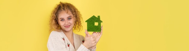 Happy house buyer A young girl holds a model of a green house in her hands The concept of green energy ecology