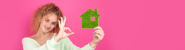 Happy house buyer A young girl holds a model of a green house in her hands The concept of green energy ecology