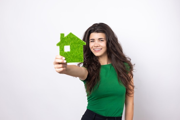 Happy house buyer A young girl holds a model of a green house in her hands The concept of green energy ecology