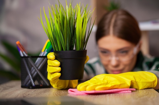 Happy house wife with spray taking care of plants at her home