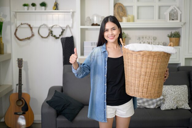 Happy housekeeper carrying a bucket cloths for laundry in the house