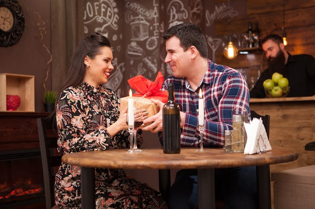 Happy husband giving wife a present in a hipster pub. Beautiful relationship.