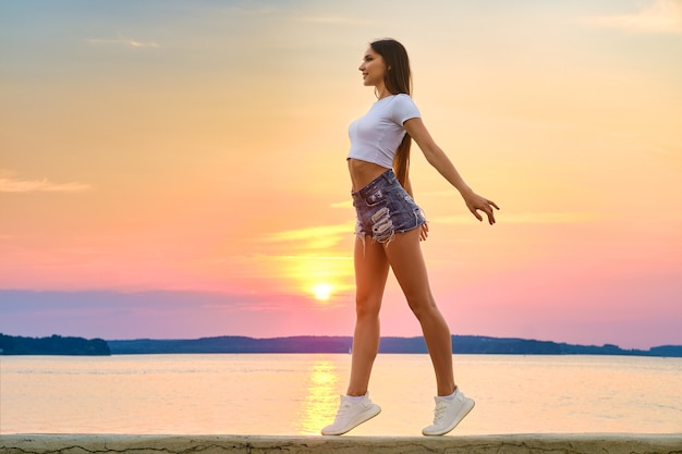 Happy and impetuous young woman enjoys freedom in sunset time