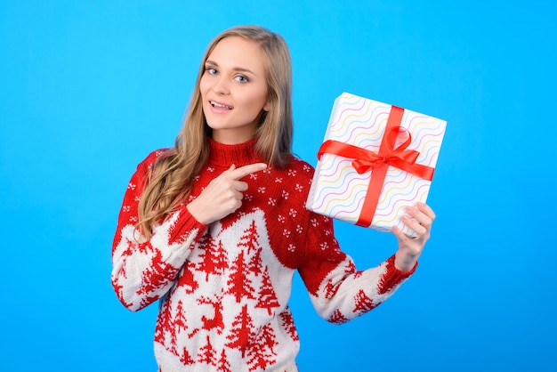 クリスマス前の気分で幸せな女性は冬休みのプレゼントを選んでいます。彼女は手に持っているギフトボックスに表示しています。