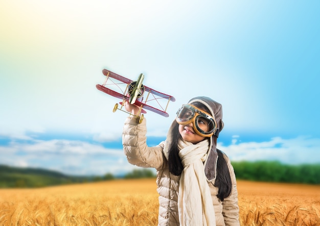 Happy Indian or asian girl kid flying a toy metal airplane or saluting against indian flag background - Kid and flying for country