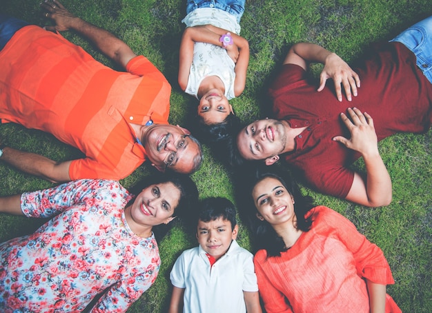 Happy Indian Asian modern family forming a circle and looking down or up at camera