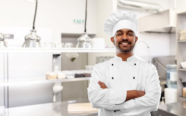 happy indian chef in toque at restaurant kitchen