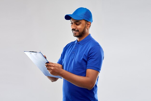 happy indian delivery man with clipboard in blue