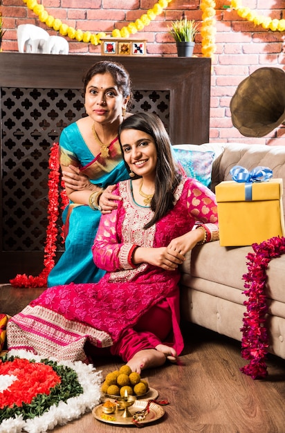 Happy Indian Family Celebrating hindu Festivals  Welcoming or performing Pooja and eating sweets in traditional wear at home decorated with Marigold Flowers