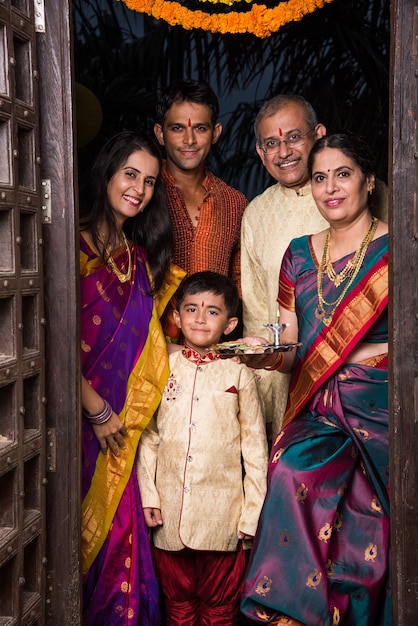 Happy Indian family entering house with puja thali through old antique door - Griha Pravesh or Gruha Pravesh