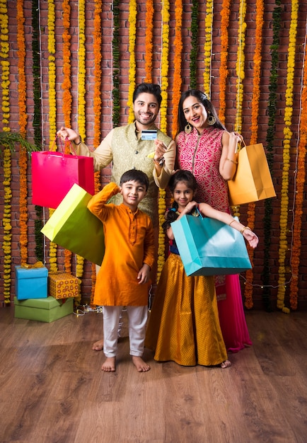 Happy Indian family festival shopping concept - holding paper bags and showing debit or credit card