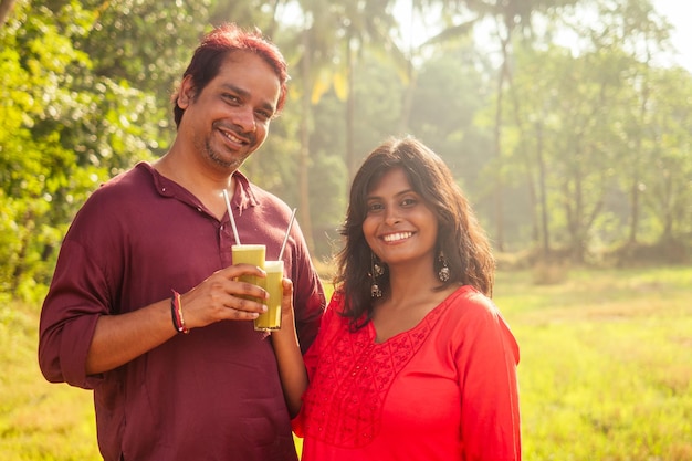 Happy indian family holding glass of fresh cane juice with eco metal tube Love to health and save planet recyclable concept