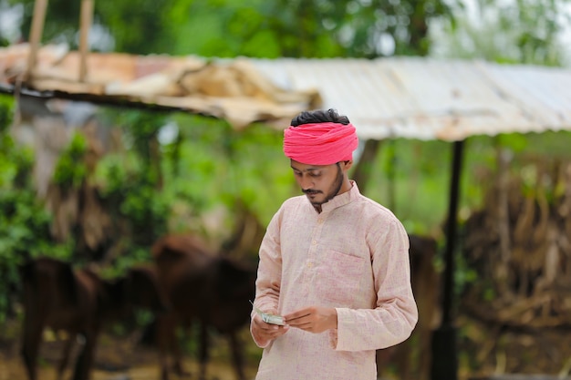 Happy Indian farmer counting money at home.