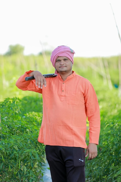 Foto felice contadino indiano che tiene in mano gli attrezzi agricoli