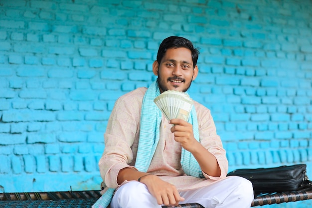 Felice contadino indiano che mostra soldi a casa