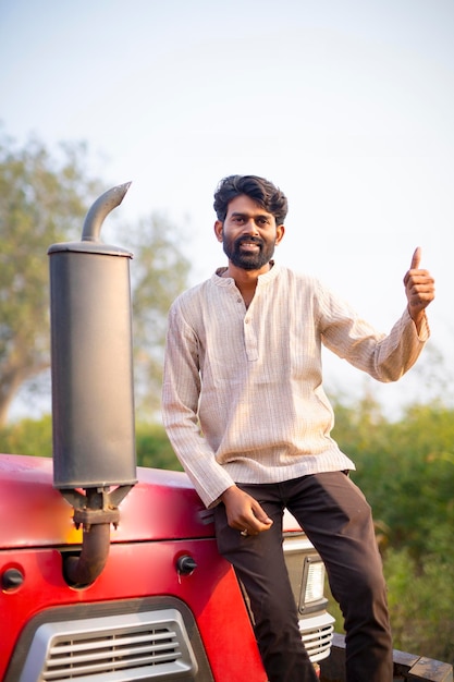 Happy Indian farmer with tractor on agricultural field