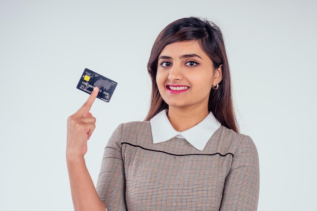 Felice ragazza indiana in possesso di carta di credito in studio sfondo bianco.