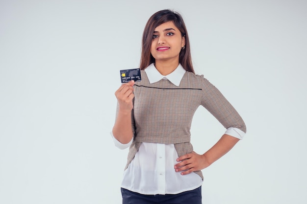 Felice ragazza indiana in possesso di carta di credito in studio sfondo bianco.