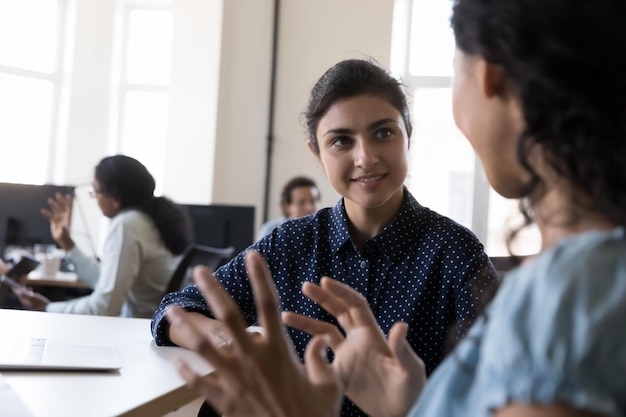 happy indian intern listening to mentor consulting corporate teacher at shared office workplace in training center discussing new professional skills smiling business education internship