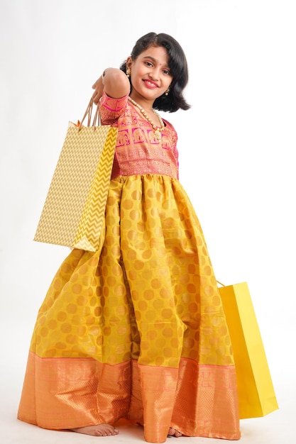 Happy Indian little girl holding shopping bags on white background