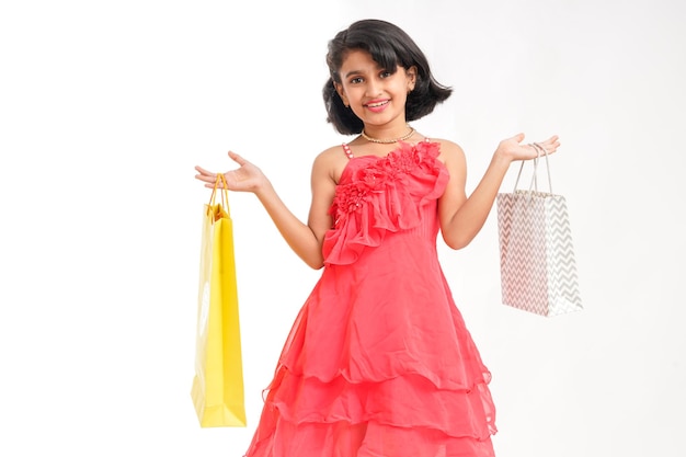 Happy Indian little girl holding shopping bags on white background