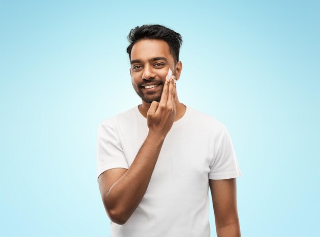 happy indian man applying cream to face