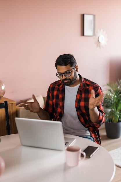 Happy indian man freelancer or entrepreneur have video conference talking working remotely online at home office video call and diversity concept