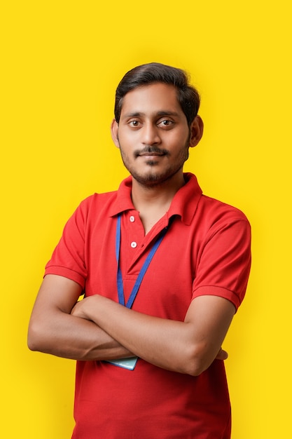 Tシャツを着て、黄色の背景に分離された表情を示す幸せなインド人。