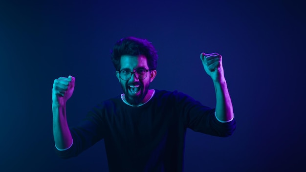 Photo happy indian man in ultraviolet neon studio background champion coding achievement level up