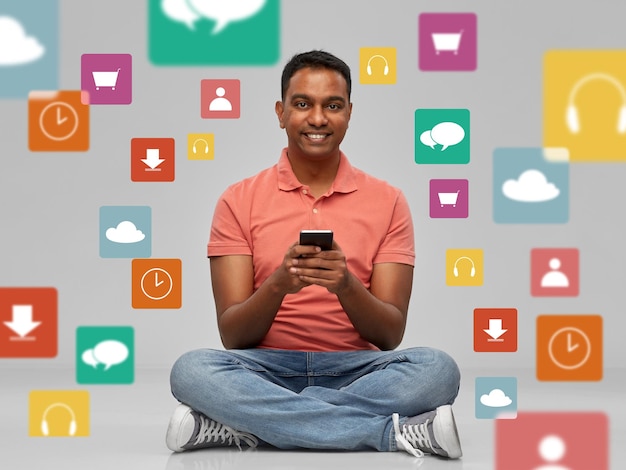 happy indian man using smartphone over app icons