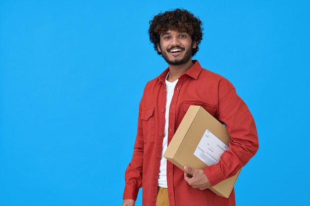 Happy indian young man holding parcel box isolated on blue background