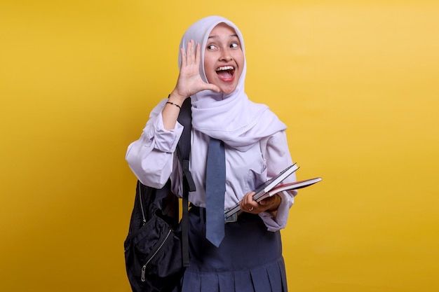 Happy Indonesian high school female muslim student shouting and looking up at copy space