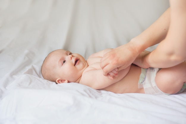 Happy infant girl doing baby massage by his mother at home. Newborn child about 5 months old