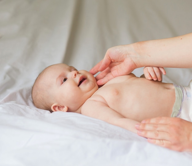 Happy infant girl doing baby massage by his mother at home. Newborn child about 5 months old