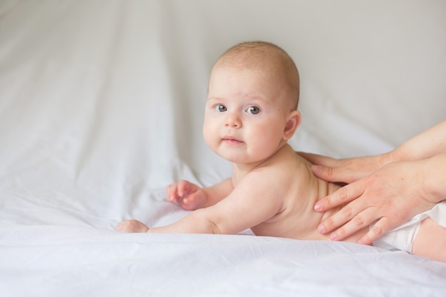 Happy infant girl doing baby massage by his mother at home. Newborn child about 5 months old