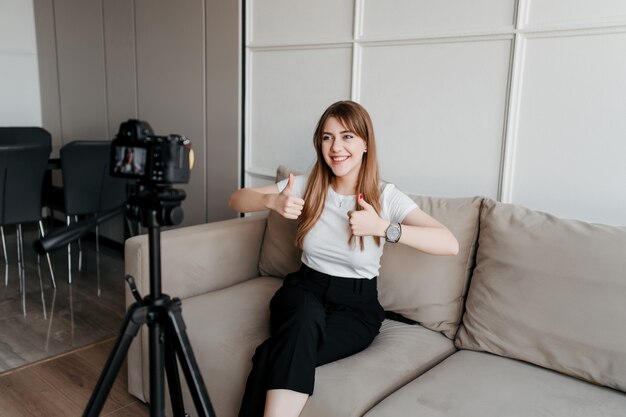 Happy influencer woman blogger showing thumbs up to the camera for her video blog on the internet