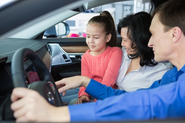Счастливая интернациональная семья покупает машину в автосалоне