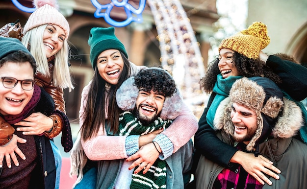 Felici amici internazionali che camminano in un luogo di viaggio invernale a cavalluccio