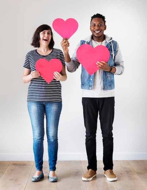 Happy interracial couple holding red hearts love and relationship concept