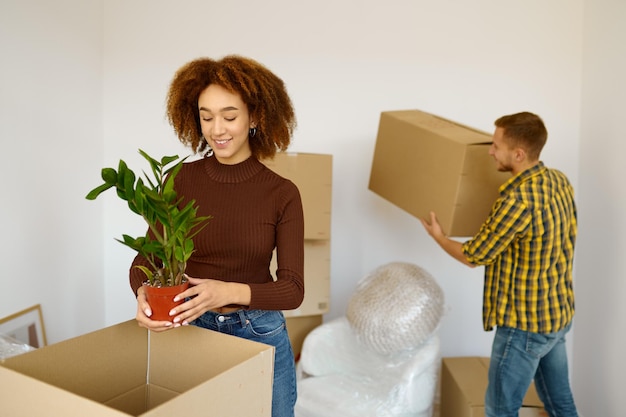 Happy interracial couple packing cardboard box for move