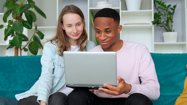 Happy interracial couple playing video games together at home