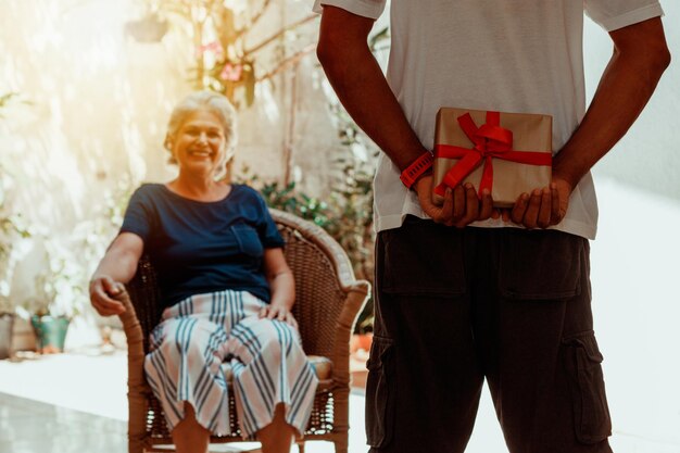 Happy interracial family son gives a gift to his mother in the\
house garden caucasian mother and her black son photo