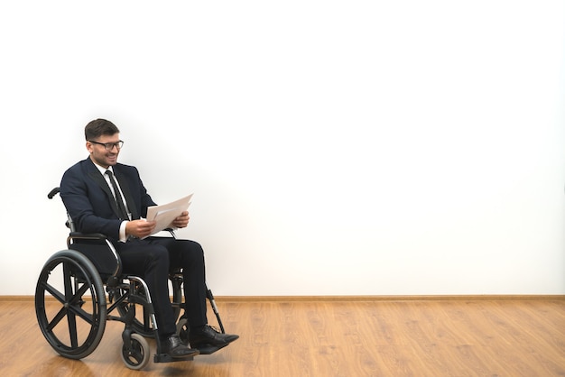 The happy invalid holding papers on the white wall background