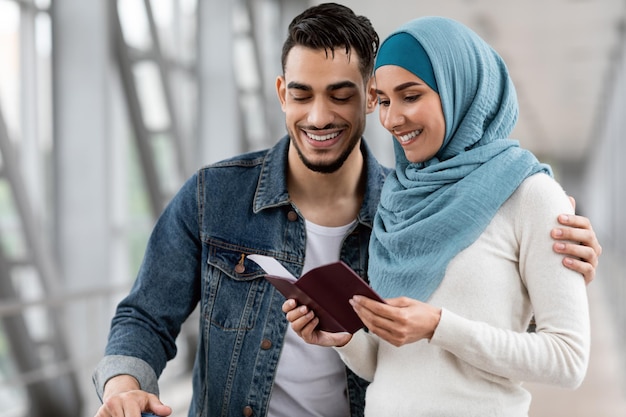 Foto felici coniugi islamici che controllano passaporti e biglietti mentre aspettano il volo in aeroporto