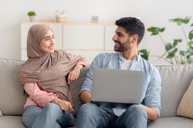 Happy islamic spouses using laptop computer together at home