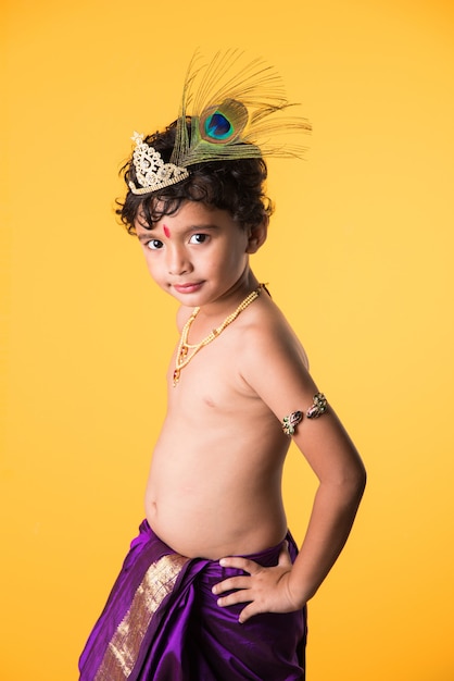 Happy Janmashtami Greeting Card showing Little Indian boy posing as Shri krishna or kanha or kanhaiya with Dahi Handi picture and colourful flowers