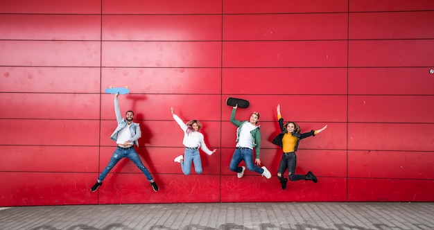 Happy jonge vrienden springen voor een rode muur achtergrond