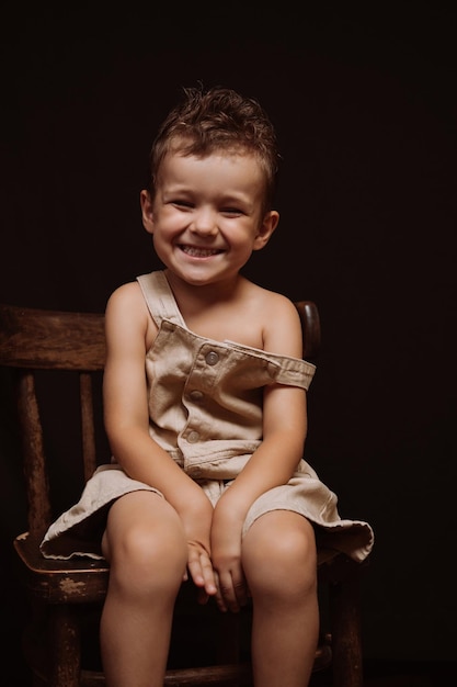 Happy joyful caucasian boy laughs sitting on a wooden chair